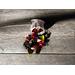 An open sachet of potpourri in vibrant red, black, and green tones scattered on a rustic wooden surface, with sunlight casting soft shadows.
